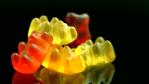 Gummy Bears rotating on black background. Colorful jelly sweets candies rotation. Closeup. 4K UHD video