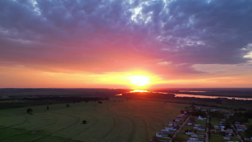 Drone shot rising over fields in Porto Maringa, toward the Rio Parana river, sunset in Brazil