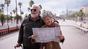Elderly Caucasian tourist couple smiling with travel map in hands looking together interest places. Senior husband and wife walking in city street enjoying pensioner vacation. Adult tourism people  - Powered by Shutterstock - Get 15% off with code: PIKWIZARD15