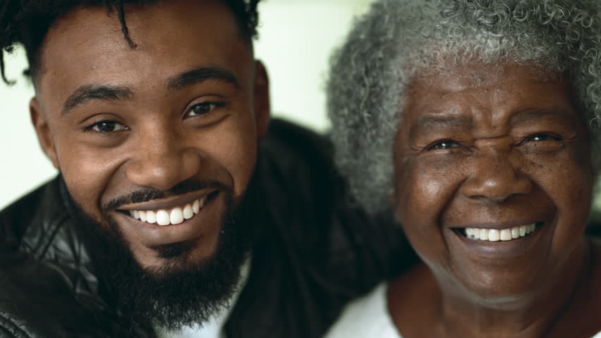 Adult grandson kissing elderly African American grandmother on the cheek in tender affectionate loving moment between two intergenerational family members Royalty-Free Stock Footage #3433044047