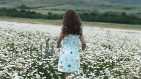 Selective focus of adorable smiling little girl kid runs through field of daisies during sunset. Concept weekend in nature. Childhood and freedom