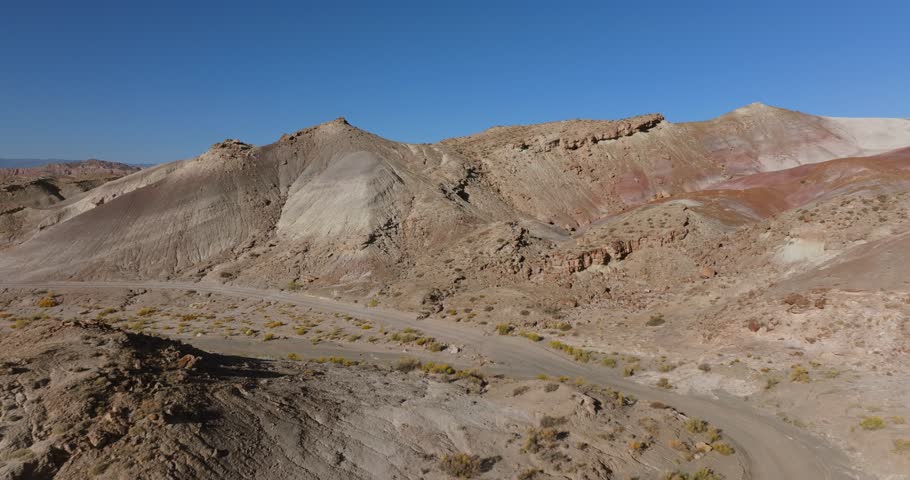 Off-road vehicle crossing Moonscape Overlook in Utah, USA. Aerial backward and blue sky for copy space