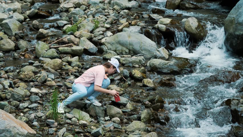Girl photographing a river in the forest. Mountain river in the Alps.