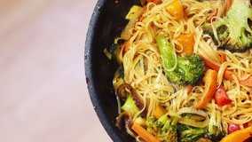 Stir fry cooking on a fry pan. Chef frying vegetables with noodles, Asian food. 4K video