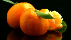 Ripe Tangerine Citrus fruits or Mandarine with leaves rotating. Beautiful Healthy organic juicy tangerine rotate over black background.  Close-up 4K UHD video 3840X2160
