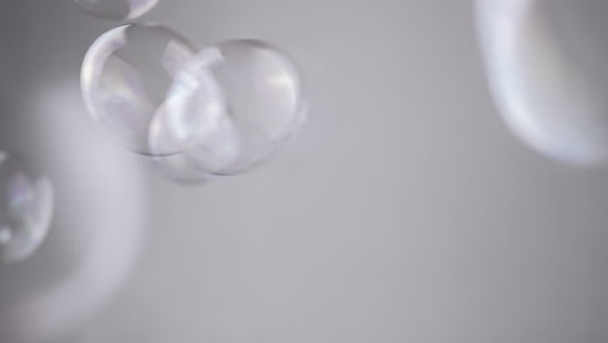 Group Soap Bubbles Moving on a Gray Background in Empty Space. Close up. Blowing large, small transparent water spheres. Abstract. Blurred motion, focus. Isolated. Chroma key. Monochrome. Slow motion.