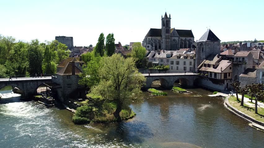 Aerial view of the medieval town of Moret-sur-Loing in Seine et Marne, France - Stone bridge spanning the river Loing towards the Burgundy Gate tower next to Our Lady of the Nativity Church Royalty-Free Stock Footage #3433169145