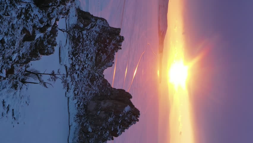 Aerial view of Shaman rock at sunset, one of sacred place in frozen lake Baikal in winter season of Siberia, Russia. Vertical video