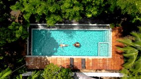 aerial drone view of swimming pool in the jungle of Krabi Thailand, aerial view with a drone above a swimming pool in the rainforest of Thailand. couple of men and women in pool during vacation - Powered by Shutterstock - Get 15% off with code: PIKWIZARD15