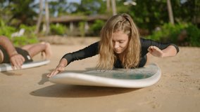 Athletic physique woman, man learn how to paddle, stand up, get on surfboard and keep balance on tropical ocean beach. Young caucasian couple taking surfing training by green palm trees in surf camp. - Powered by Shutterstock - Get 15% off with code: PIKWIZARD15