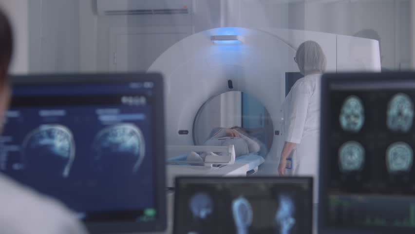Professional female doctor controls MRI or CT or PET scan with patient undergoing procedure. Camera changes view to monitors with displayed brain scans results in control room. Healthcare Service. Royalty-Free Stock Footage #3433465793