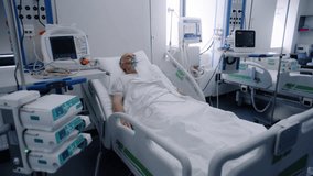 Sick elderly man in oxygen mask sleeps in bed in hospital ward. Old patient during lung ventilation. Equipped emergency room in clinic. Intensive care coronavirus department in modern medical center. - Powered by Shutterstock - Get 15% off with code: PIKWIZARD15