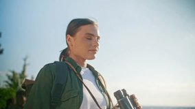 Charming Caucasian woman using binoculars and looking at something with excitement. Feeling happy and positive. Active lifestyle. Getting closer with nature. Searching for lost trail. - Powered by Shutterstock - Get 15% off with code: PIKWIZARD15
