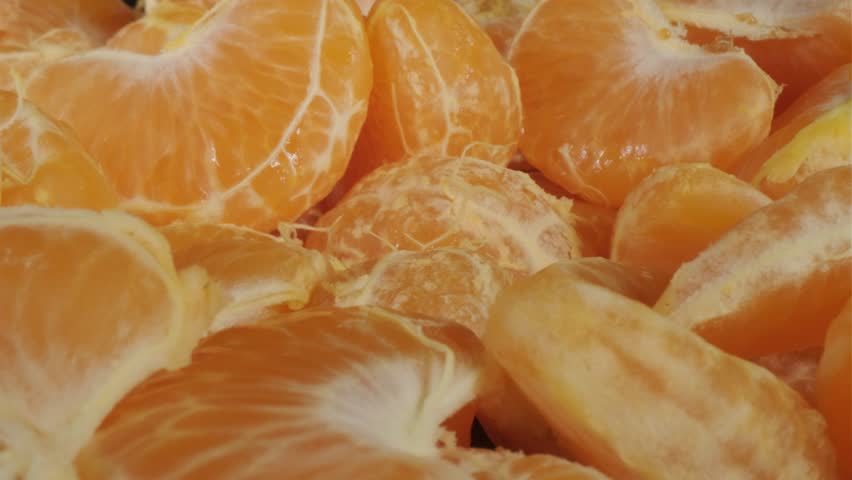 Peeled tangerines on a black background. Slices of tangerine or mandarin fruit close up