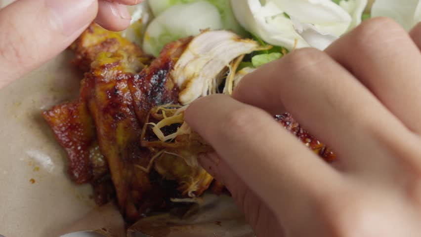 Close up shot Hands eat chicken with fingers indonesia style, ayam bakar lalapan