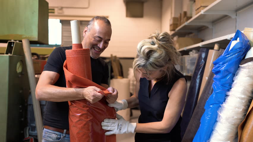 professional stylist fashion designer working together while choosing the right textile product for clothing production inside a factory