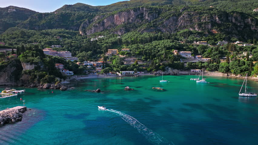 Cristal clear turquoise waters of Corfu, tourist destination with verdant landscapes. Aerial view of the picturesque village and Paleokastritsa Beach resort in Greece.