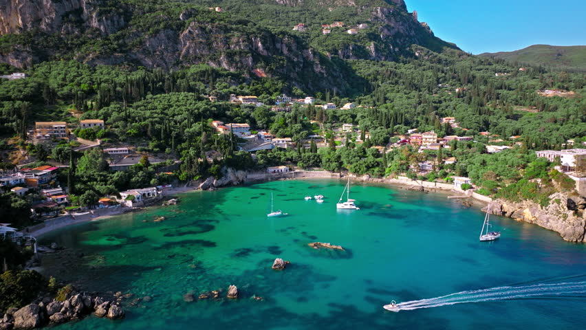 Cristal clear turquoise waters of Corfu, tourist destination with verdant landscapes. Aerial view of the picturesque village and Paleokastritsa Beach resort in Greece.