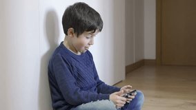 Excited child playing with smartphone online at home
