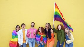 Diverse group of young people celebrating gay pride festival day - Lgbt community concept with guys and girls hugging together outdoors - Multiracial trendy friends standing on a yellow background  - Powered by Shutterstock - Get 15% off with code: PIKWIZARD15