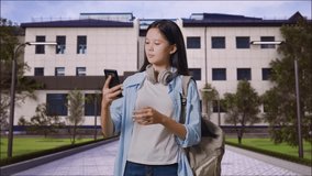 Asian Teen Girl Student With A Backpack And Some Books Having A Video Call On Smartphone While Standing in Front of a School Building