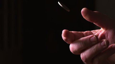Slow motion stylized shot of male flipping a coin in high key lighting.