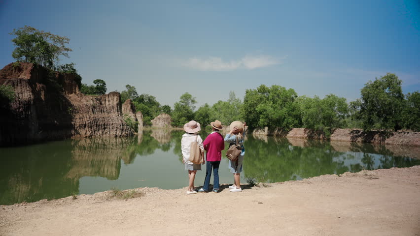Three Asian women are best friends, come travel nature, relaxing, together after retirement, using pension money, stand by water admire atmosphere, beautiful natural view, amazed by beautiful things.