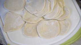 Close-up view of female hands making dumplings with ground meat in domestic kitchen at home. Soft focus. Real time handheld video. Homemade food theme.
