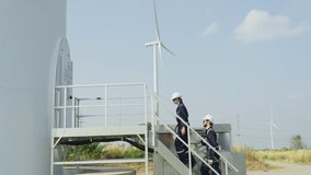 Wide shot of one professional technican workers give the document to her coworker walk to base area of windmill or wind turbine. - Powered by Shutterstock - Get 15% off with code: PIKWIZARD15
