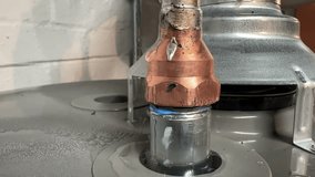 A closeup view of a leaking copper pipe on the top of a hot water heater.	 - Powered by Shutterstock - Get 15% off with code: PIKWIZARD15