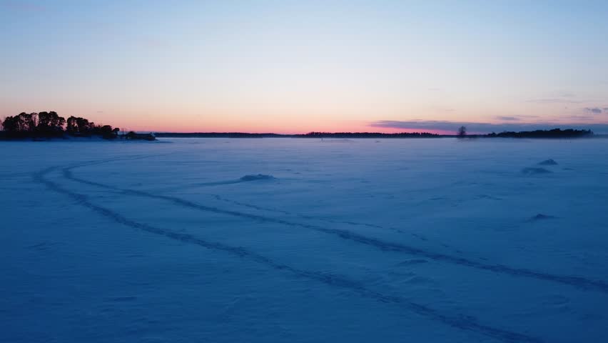 Aerial view risiing over snowy sea ice, vibrant winter dusk on the gulf of Finland