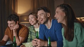 People laughing at tv comedy on weekend evening meeting close up. Happy young friends clinking beer bottles enjoying television show together. Joyful millennials having fun at night hangout in home. - Powered by Shutterstock - Get 15% off with code: PIKWIZARD15