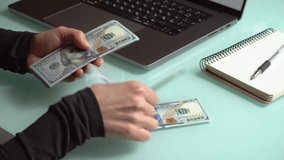 4K close up footage of female hands counting 100 dollar banknotes in front of laptop screen with diagrams. Home finance concept