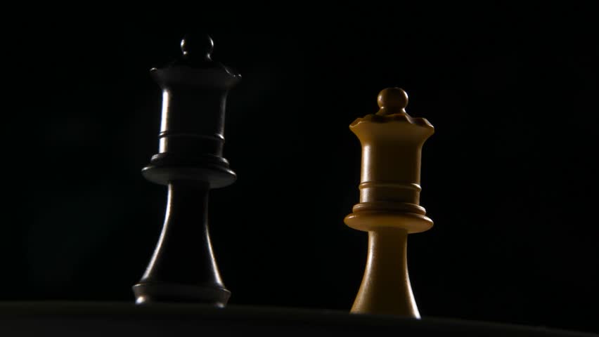 Close-up moving shot of black and white queen chess pieces.