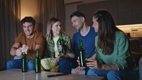 Chilling friends clinking beer bottles relaxing at home couch together. Smiling happy mates sitting sofa preparing to watch movie with popcorn. Carefree young people enjoy night gathering in apartment - Powered by Shutterstock - Get 15% off with code: PIKWIZARD15