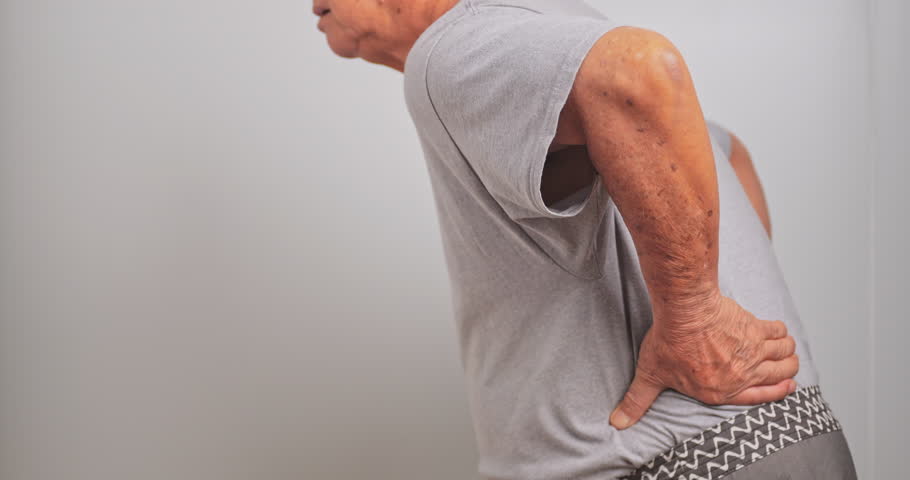 An old Asian man has back pain after lifting a heavy object.