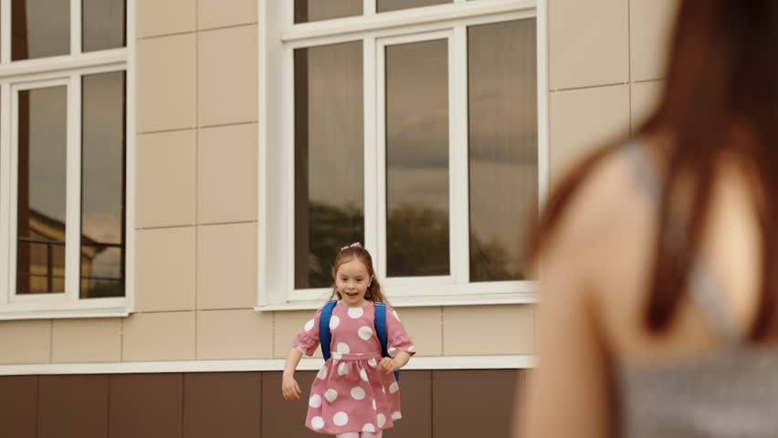 Overjoyed cute little girl pupil running to hugging mother meeting after school lesson closeup slowmo. Happy female child kid embracing mom with love and tenderness at schoolyard campus outdoor Royalty-Free Stock Footage #3434085563