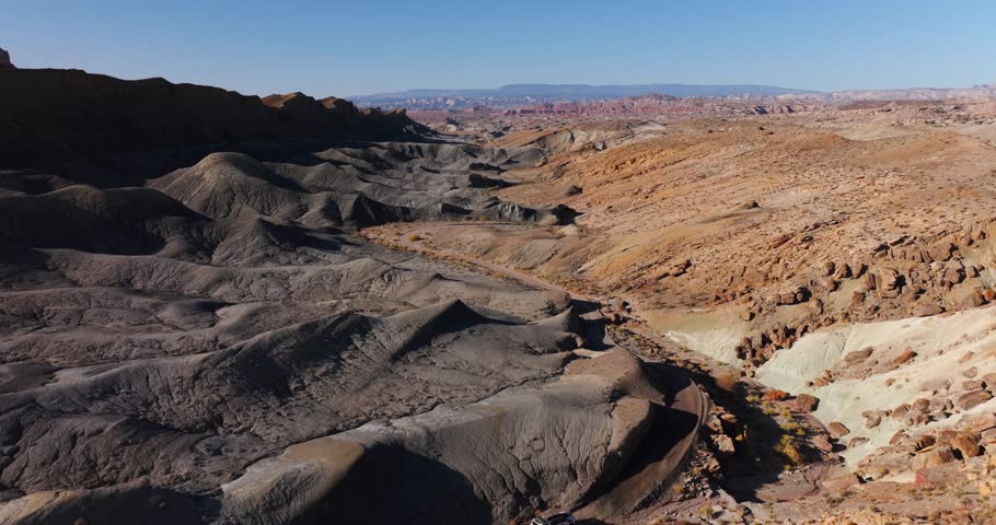 Off-road vehicle crossing landscape changing shape and color, Moonscape Overlook in Utah, USA. Aerial drone flyback