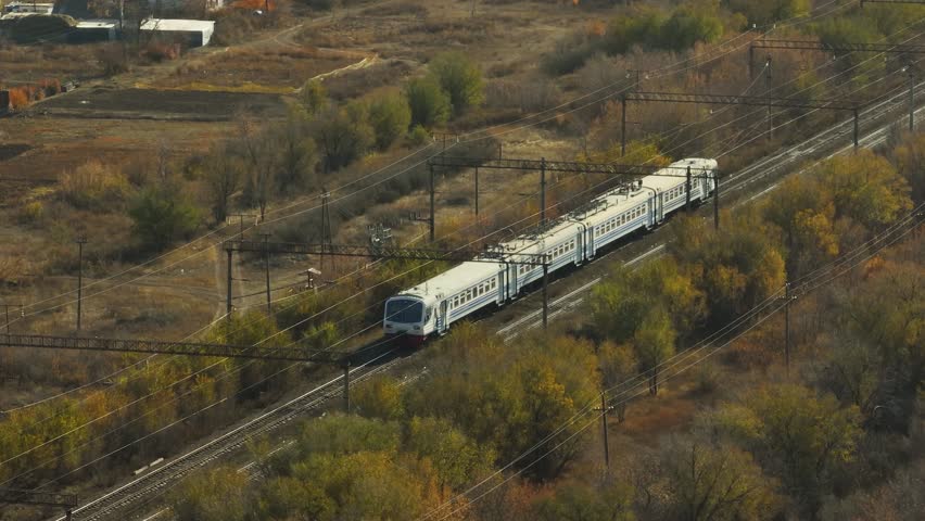Passenger train an electric locomotive start two sided straight railway arid flat steppe - Aerial drone view at autumn sunny day