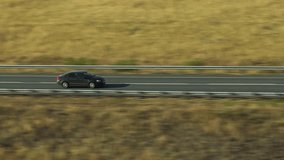 One black sedan car driving, travel on empty straight asphalt road freeway through empty arid steppe plain at summer sunny day. Aerial drone wide into the distance view. - Powered by Shutterstock - Get 15% off with code: PIKWIZARD15