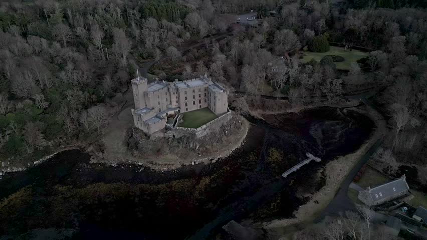 Dunvegan castle on the isle of skye, surrounded by woodlands and water, under overcast skies, aerial view