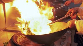 Close up of a chef cooking in a restaurant kitchen frying vegetables in the Chinese Sichuan style.  - Powered by Shutterstock - Get 15% off with code: PIKWIZARD15