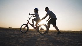 Happy family. Father teaches daughter to ride bike in park. Daughter riding bike for first time. Kid dream of traveling by bike. Girl is learning to ride a bike. Father helping hand to daughter - Powered by Shutterstock - Get 15% off with code: PIKWIZARD15