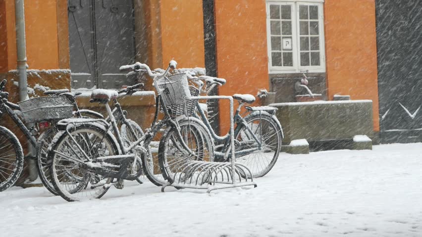 Snowing in city, snowflakes falling on standing bikes in Copenhagen