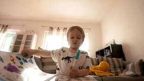 In this video, a young boy can be seen sitting at a table while holding a toothbrush in his mouth.