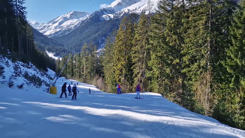 Winter season at Bansko ski resort in Bulgaria with a view to the skiers having fun on the slope and Pirin mountains in the background