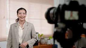 Asian woman standing in office, occupation is construction engineer, talking, teaching about work related career that do, recording clip by placing video camera in front, speak fluently.