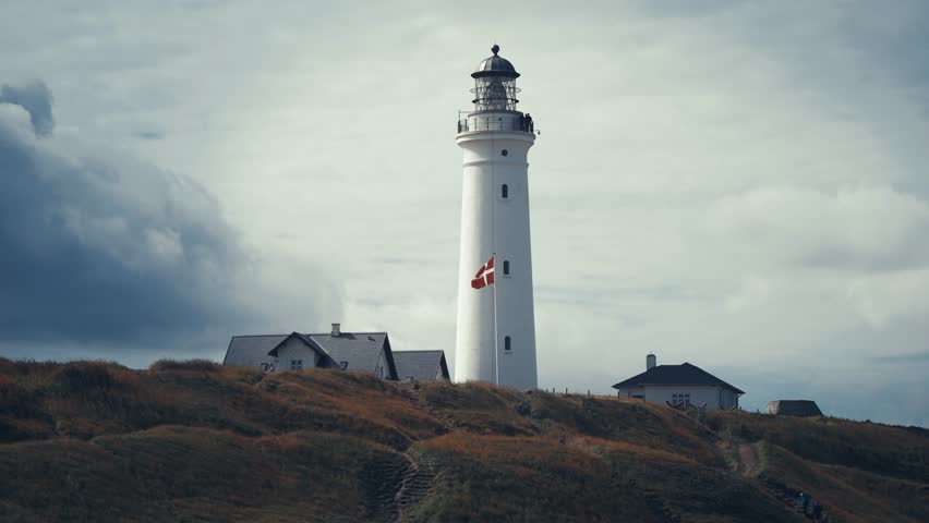 Dark clouds crawl above the lighthouse. The Danish flag flutters in the wind.