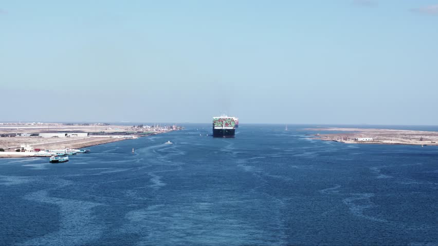 Wide shot of a large container vessel entering Suez canal in Port Said. 