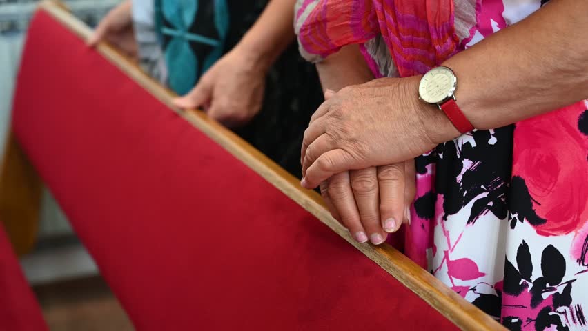 Elderly women prays in the church. Close up of hands of a woman during prayer.  